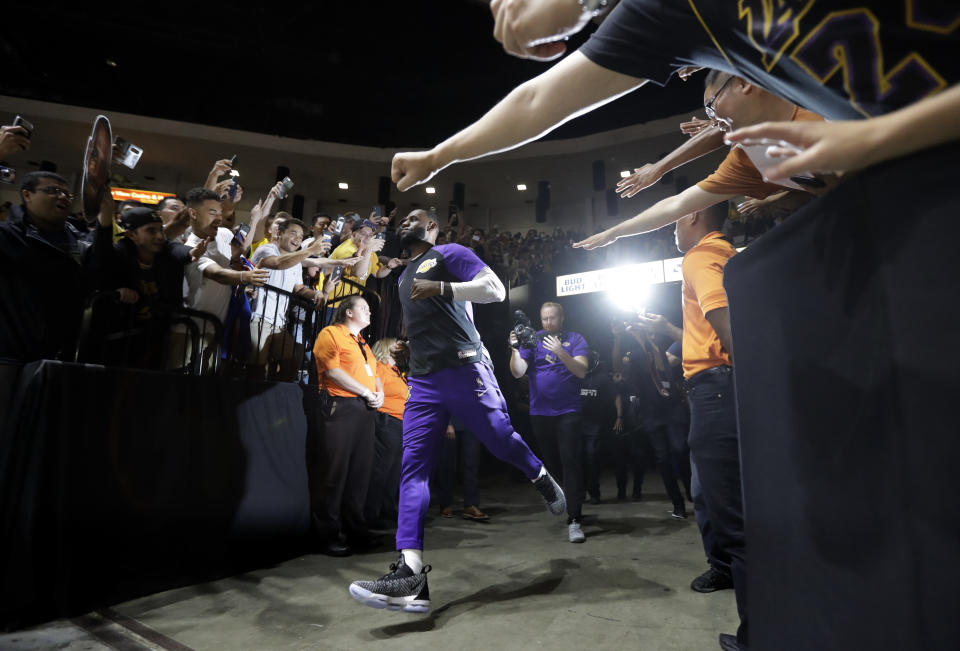 Los Angeles Lakers forward LeBron James runs past fans on his way to the court before an NBA preseason basketball game against the Denver Nuggets, Sunday, Sept. 30, 2018, in San Diego. (AP Photo/Gregory Bull)