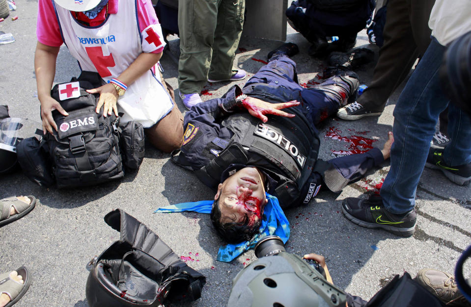 EDS NOTE GRAPHIC CONTENT - A riot police officer lies motionless after a massive head injury during a clash with protesters in Bangkok, Thailand, Tuesday, Feb. 18, 2014. Emergency medical officials say that one civilian was killed and 50 people were injured in clashes between Thai police and anti-government protesters in Bangkok. Multiple gunshots were heard midday Tuesday at the site in a historic section of town near the Government House, but it wasn't clear who was firing. (AP Photo/Wally Santana)