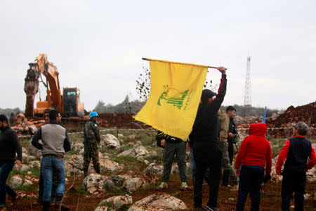 FILE PHOTO: A man holds a Hezbollah flag at Meis al-Jabal village in south Lebanon, December 9, 2018. REUTERS/Aziz Taher/File Photo