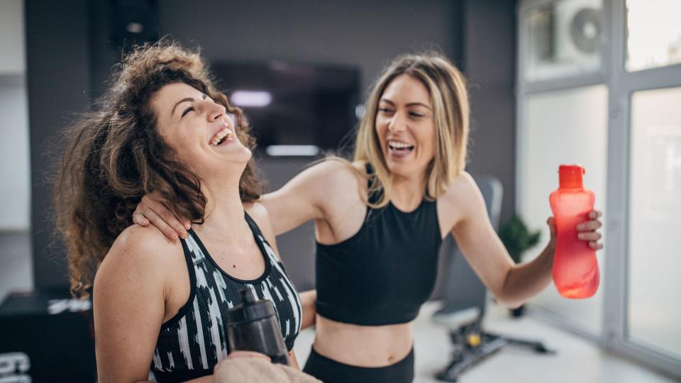 Two women laughing together at the gym