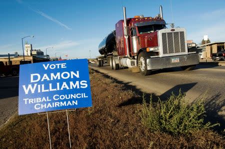 Oil field traffic passes a campaign sign for Three Affiliated Tribes council chairman candidate Damon Williams in New Town on the Fort Berthold Reservation in North Dakota, November 1, 2014. REUTERS/Andrew Cullen