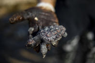 FILE - In this Feb. 20, 2021 file photo, a woman holds a dead sea turtle covered in tar from an oil spill in the Mediterranean Sea in Gador nature reserve near Hadera, Israel. Israel’s new environmental protection minister, Tamar Zandberg laid out her agenda in an interview with The Associated Press ahead of the upcoming U.N. climate conference in Glasgow where she says Israel, a nation of 9.3 million people, has the potential to be a key player. A secretive oil-pipeline deal between Israel and the United Arab Emirates that has raised fears that an oil spill might one day destroy the Red Sea coral reefs, prized by scientists for their unique resilience against warming seas, is now under review by the government. (AP Photo/Ariel Schalit, File)