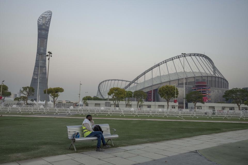 FILE - A migrant worker sleeps on a bench before his early morning shift, in front of Khalifa International Stadium, which will host matches during FIFA World Cup 2022, in Doha, Qatar, Saturday, Oct. 15, 2022. Migrant laborers who built Qatar's World Cup stadiums often worked long hours under harsh conditions and were subjected to discrimination, wage theft and other abuses as their employers evaded accountability, a rights group said in a report released Thursday. (AP Photo/Nariman El-Mofty, File)