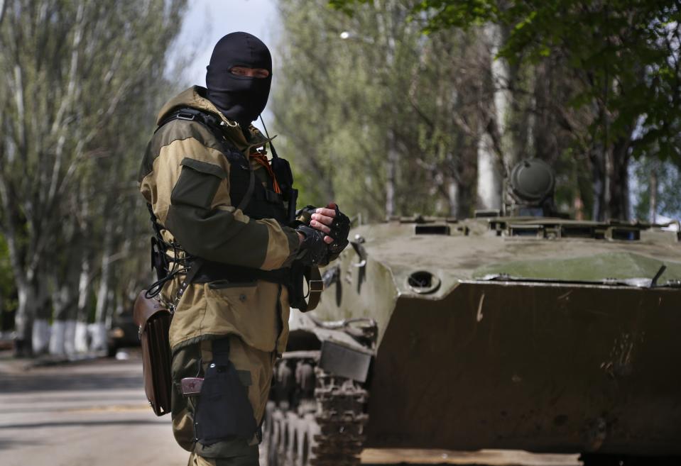 A pro-Russian masked gunman patrols a street in the center of Slovyansk, eastern Ukraine, Wednesday, April 23, 2014. Pro-Russian gunmen in eastern Ukraine admitted on Wednesday that they are holding an American journalist, saying he was suspected of unspecified "bad activities." (AP Photo/Sergei Grits)