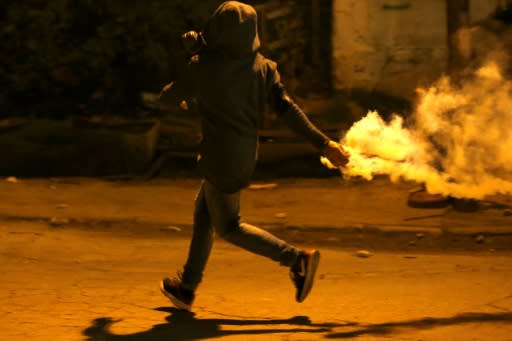 A Palestinian protester throws back a tear gas canister lobbed by Israeli soldiers during an incursion into the West Bank city of Ramallah on January 7, 2019