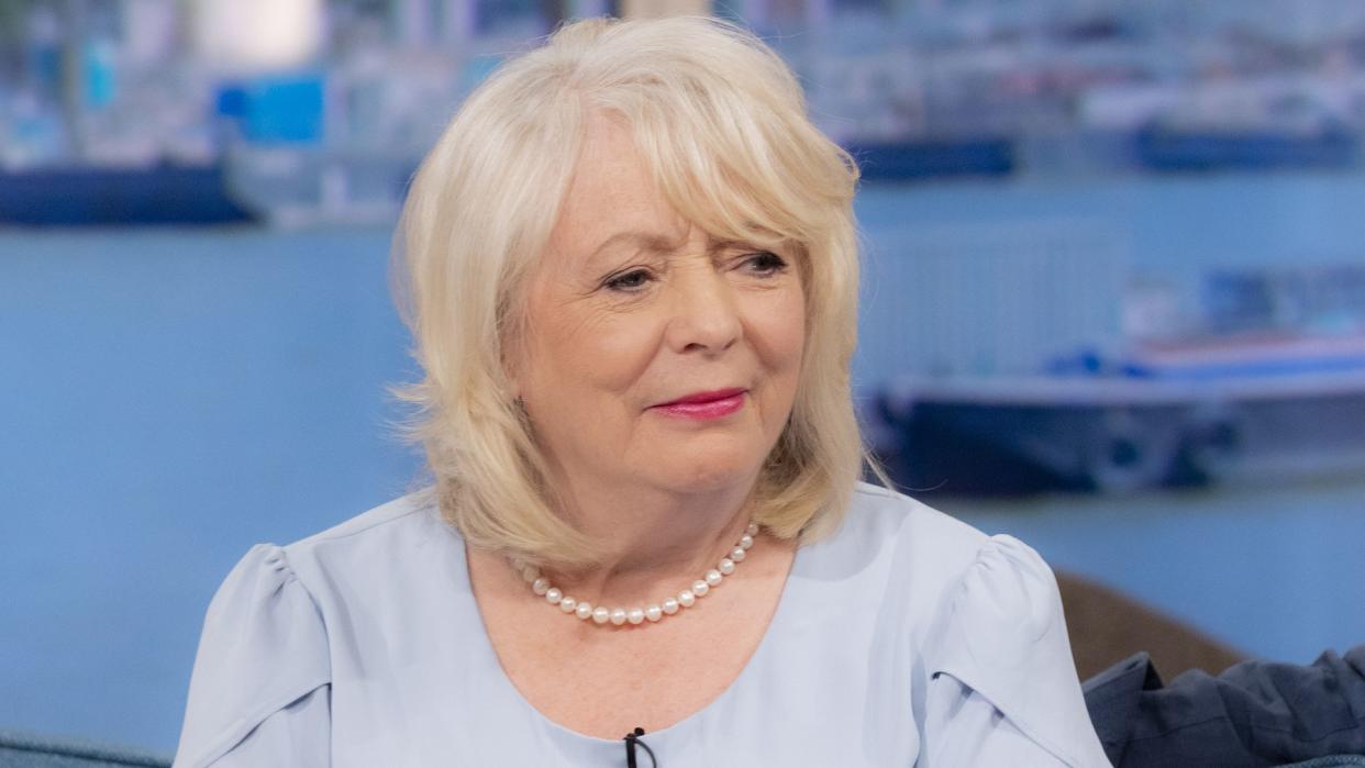 Alison Steadman looking sad in a blue dress and pearl necklace