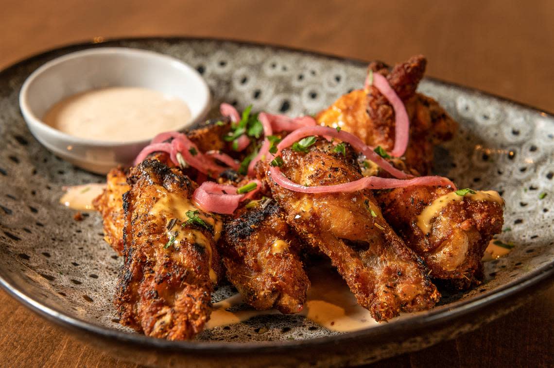 Dry rubbed wings topped with Alabama White Sauce and Blistered Onion Confit at The Crunkleton.