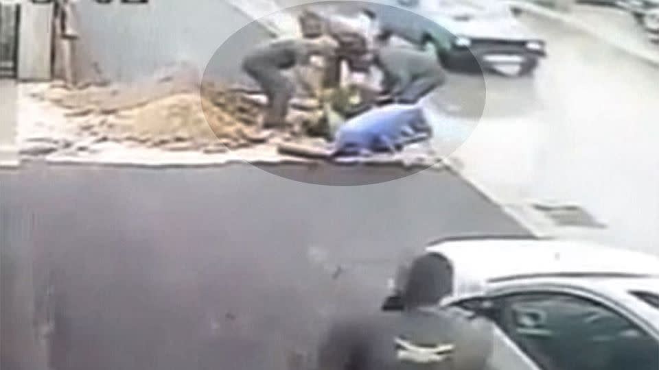 Bystander rush to the aid of the woman and pull her from the manhole. Photo: YouTube