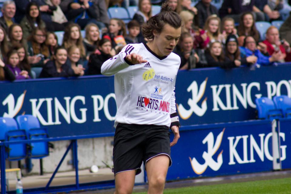 Harry Styles on the field sporting a white vest and black shorts