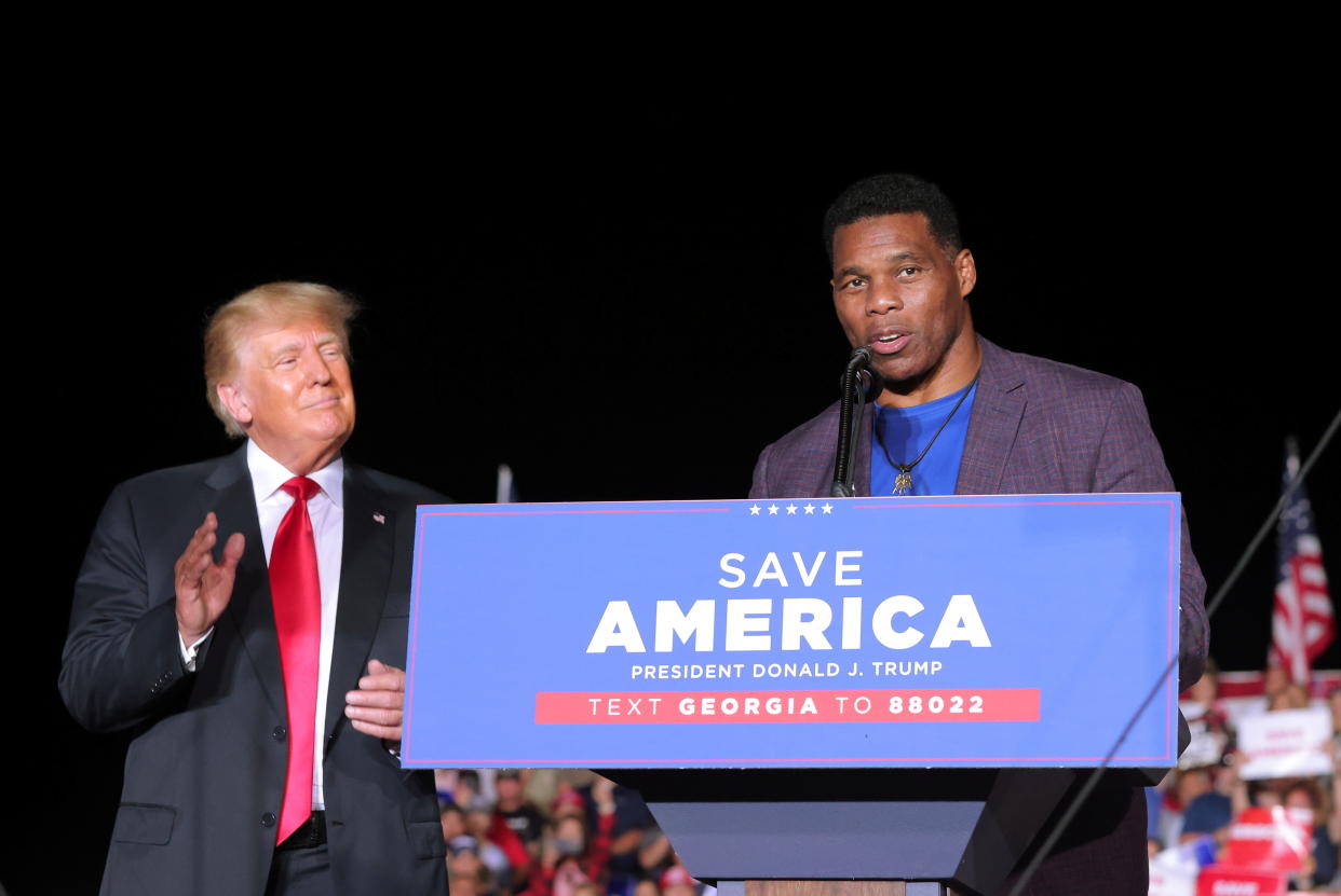 Herschel Walker speaks at a rally, as former President Donald Trump applauds, in Perry, Ga. (Reuters)