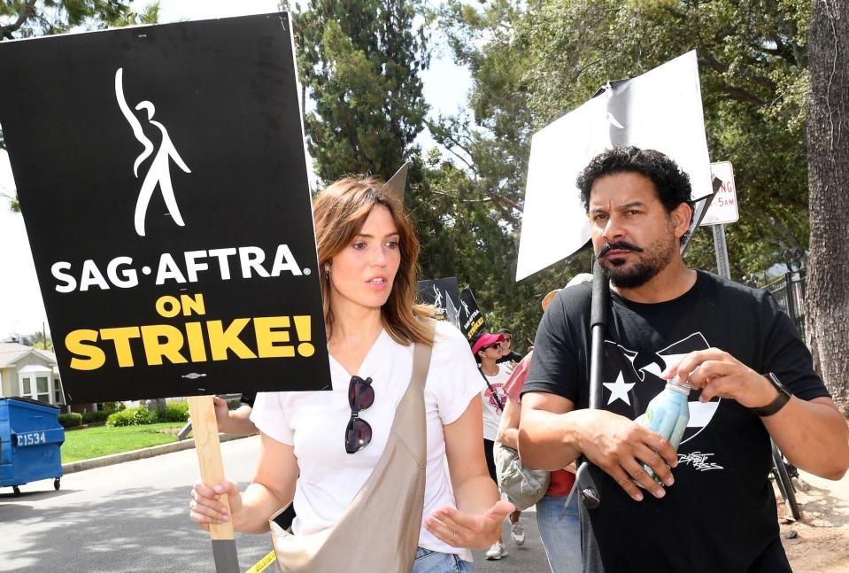 US actress Mandy Moore (L) and US actor John Huertas join members of the Writers Guild of America and the Screen Actors Guild as they walk a picket line outside of Walt Disney Studios in Burbank, California, on August 1, 2023. Tens of thousands of Hollywood actors went on strike at midnight July 14, 2023, effectively bringing the giant movie and television business to a halt as they join writers in the first industry-wide walkout for 63 years. (Photo by VALERIE MACON / AFP) (Photo by VALERIE MACON/AFP via Getty Images)