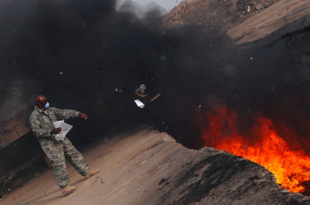 A US soldier throws trash into a burn pit in Iraq in 2008  (U.S. Air Force photo/Senior Airman Julianne Showalter)
