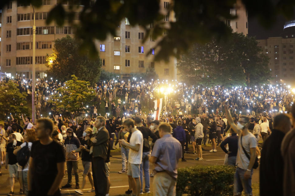 Protesters light up their mobile devices as they gather after the Belarusian presidential election in Minsk, Belarus, Sunday, Aug. 9, 2020. Police and protesters clashed in Belarus' capital and the major city of Brest on Sunday after the presidential election in which the authoritarian leader who has ruled for a quarter-century sought a sixth term in office. (AP Photo/Sergei Grits)