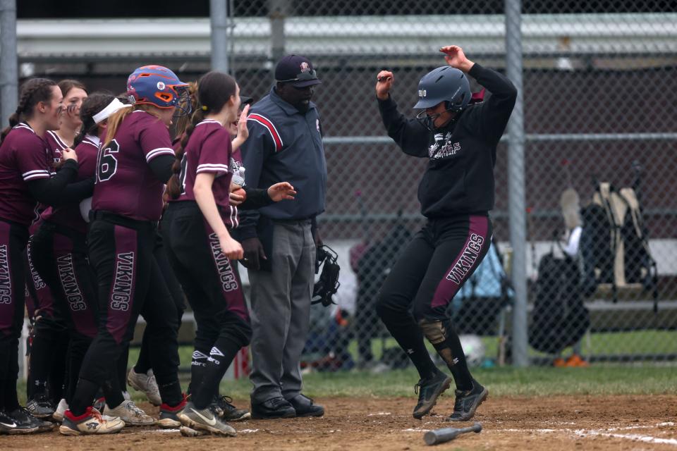 Waterloo senior Mackensi Kehrer leaps onto home plate to her waiting teammates after hitting a home run during the second game of Thursday's doubleheader against the McDonald Blue Devils at Waterloo High School.