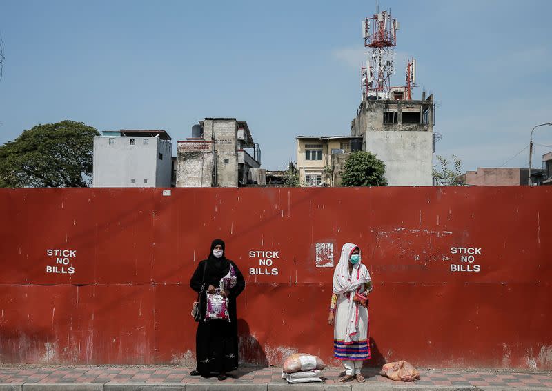 Two Muslim women wearing protective masks stand on a side of the main road after receiving free food items from Sri Lankan Air-force in Colombo