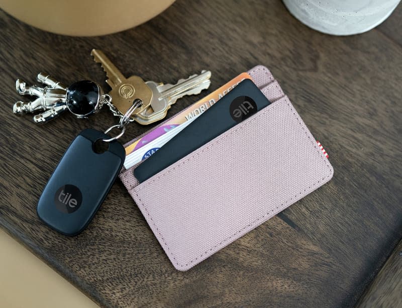 purple card case and keys with black Tile trackers