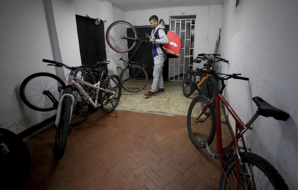 Venezuelan bicycle courier Samuel Romero who works with Rappi gets ready to start his work day in Bogota, Colombia, Wednesday, July 17, 2019. "I am grateful to have some work" says Romero, who arrived in Colombia last year. "But you really have to devote tons of time to this to make any decent money." (AP Photo/Fernando Vergara)
