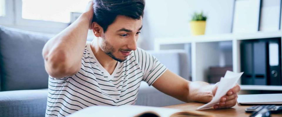 Worried man counting home finances sitting on floor in living room