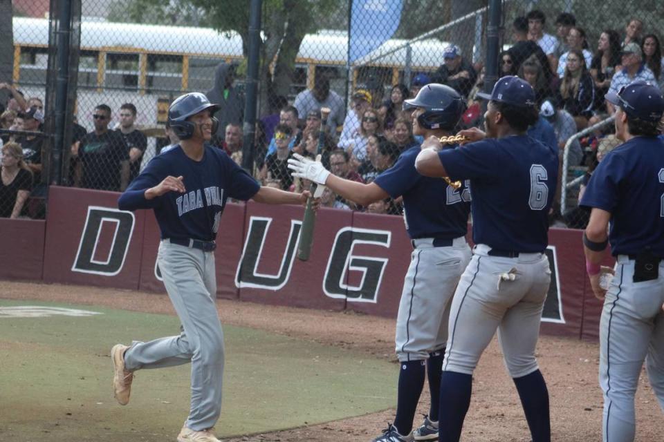 Javi Miranda is greeted by his Taravella teammates after scoring a first inning run during the Trojans’ 3-2 loss to Douglas in a Region 4-7A baseball semifinal on Friday.