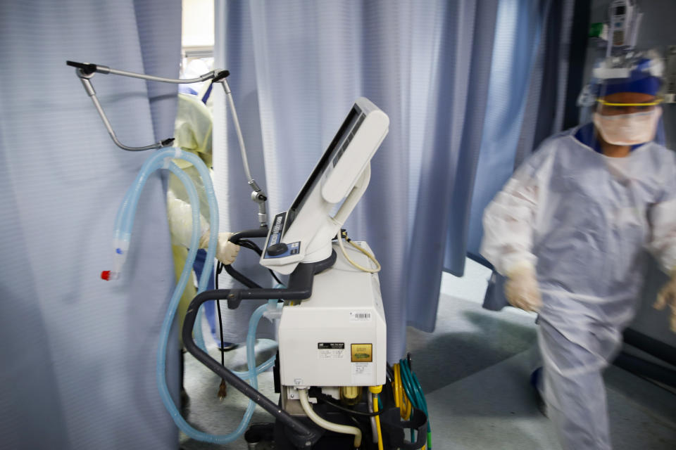 A nurse pulls a ventilator into an exam room where a patient with COVID-19 went into cardiac arrest Monday, April 20, 2020, at St. Joseph's Hospital in Yonkers, N.Y. The emergency room team successfully revived the patient. (AP Photo/John Minchillo)