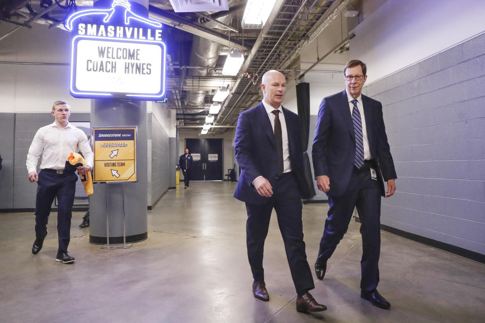 New Nashville Predators NHL hockey team head coach John Hynes, second from right, walks to a news conference with Predators general manager David Poile, right, on Tuesday, Jan. 7, 2020, in Nashville, Tenn. The Predators hired Hynes, the former New Jersey Devils coach, as the third coach in franchise history after firing Peter Laviolette. (AP Photo/Mark Humphrey)