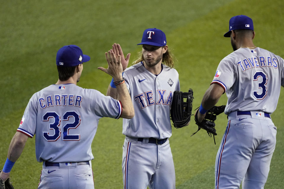 Texas Rangers' Evan Carter (32), Travis Jankowski, center, and Leody Taveras (3) celebrate after Game 4 of the baseball World Series Tuesday, Oct. 31, 2023, in Phoenix. The Rangers won 11-7. (AP Photo/Ross D. Franklin)