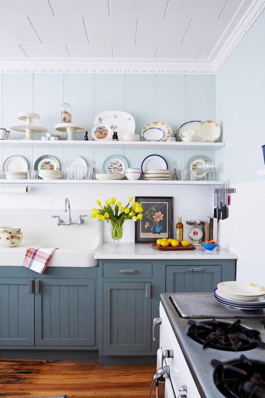 a farmhouse kitchen with blue lower cabinets and open shelves