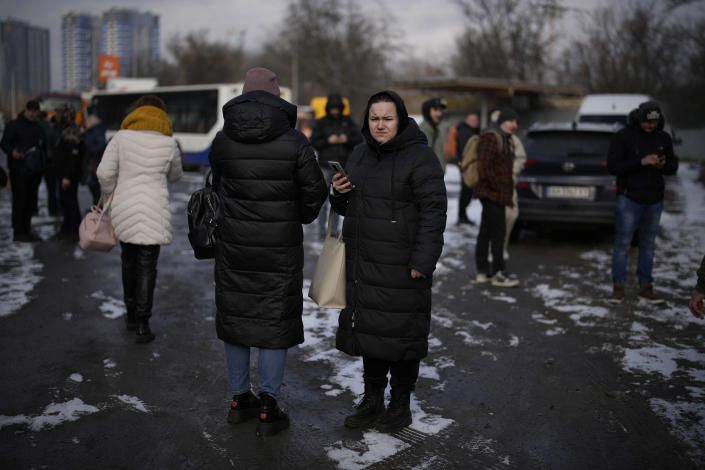 People wait on a street blocked by police after a rocket attack in Kyiv, Ukraine, Thursday, Jan. 26, 2023. (AP Photo/Daniel Cole)