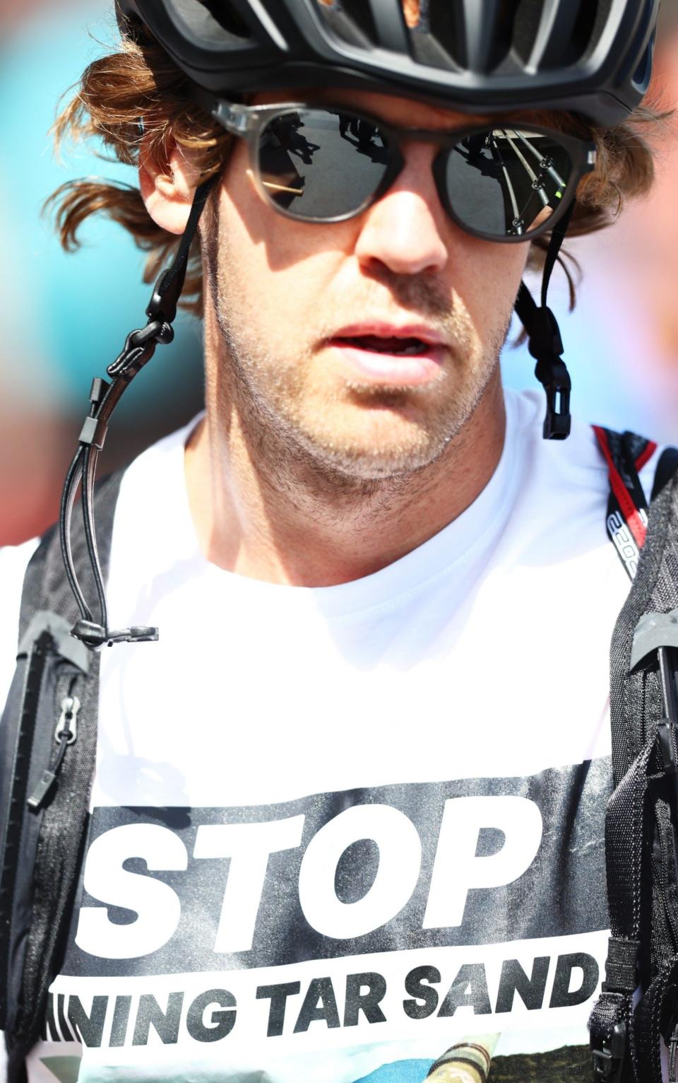 Sebastian Vettel of Germany and Aston Martin F1 Team arrives in the Paddock wearing a shirt with the slogan "Stop Mining Tar Sand" prior to practice ahead of the F1 Grand Prix of Canada at Circuit Gilles Villeneuve on June 17, 2022 in Montreal, Quebec. 