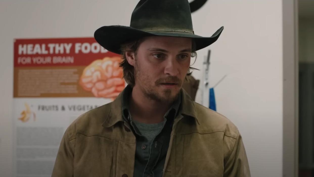  A screenshot of Luke Grimes as Kayce in Yellowstone standing in a doctor's office. 