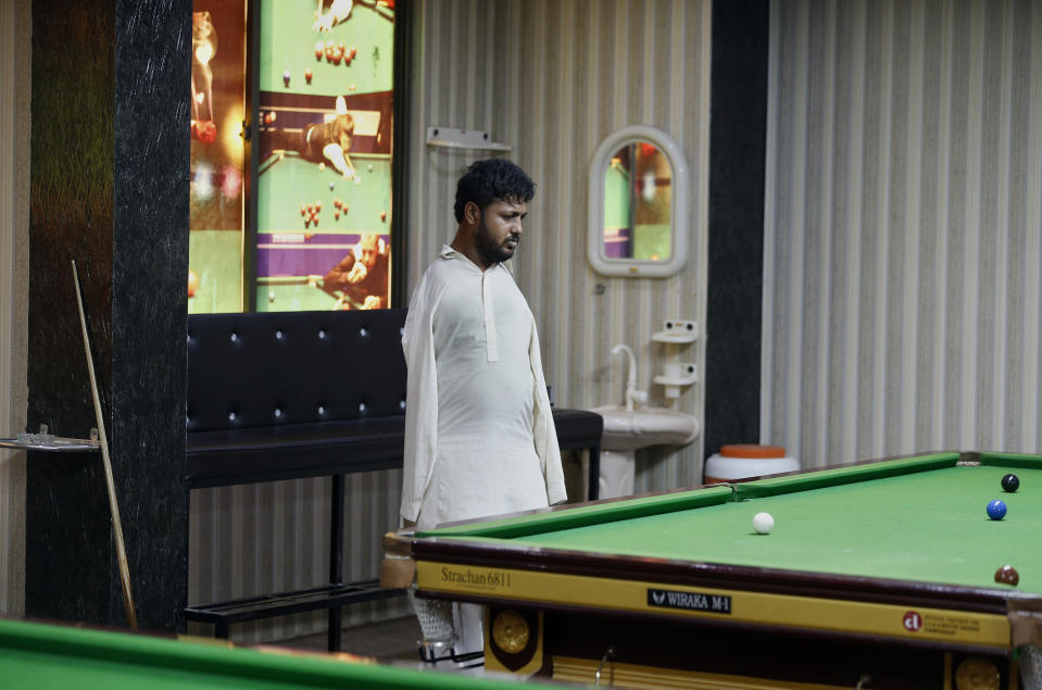 Mohammad Ikram observes during playing snooker at a local snooker club in Samundri town, Pakistan, Sunday, Oct. 25, 2020. Ikram, 32, was born without arms, but everyone simply admires his snooker skills when he hits the cue ball with his chin and pots a colored ball on a snooker table. He lives in a remote rural town of Punjab province and his physical disability doesn't come in his way to fulfill his childhood dream of playing the game of snooker. (AP Photo/Anjum Naveed)