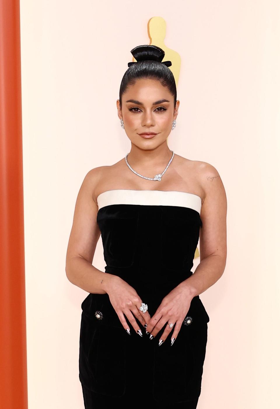 Vanessa Hudgens in a strapless gown with a diamond necklace and her hair in a sleek topknot
