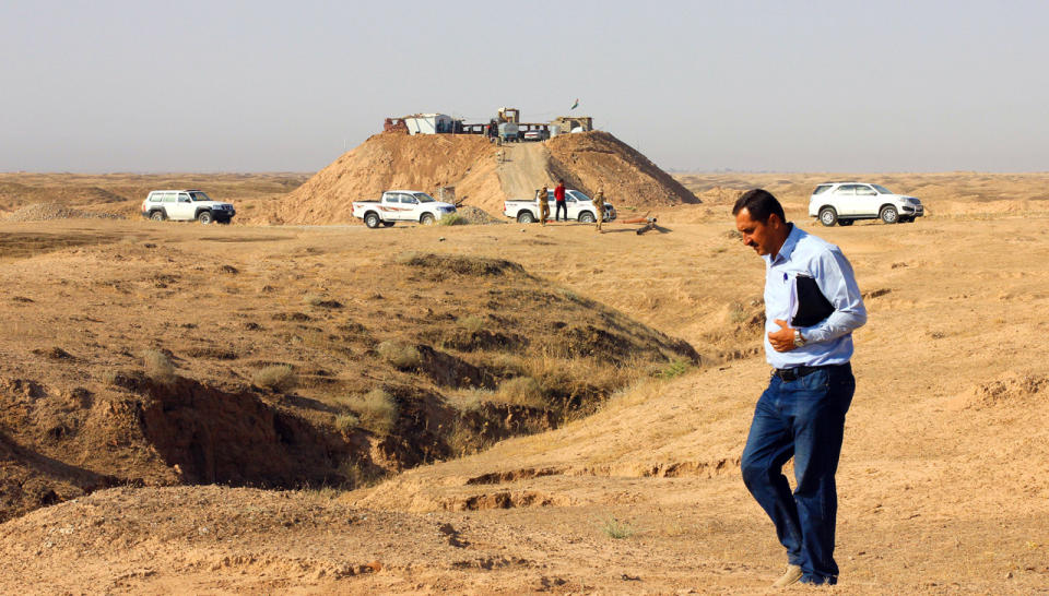 An Iraqi official checks in on progress made by the Swiss Foundation for Mine Action in its efforts to demolish explosives left by ISIS. He walks along the trenches and hills behind the frontline, and a hill fortified by Peshmerga forces to prevent ISIS from getting a view of the demining teams. (Photo: Ash Gallagher for Yahoo News)