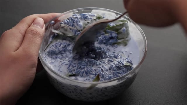 Stuffing pandan leaves into blue rice and thick coconut milk