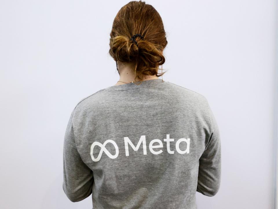 A woman wearing a grey t-shirt with Meta's logo.