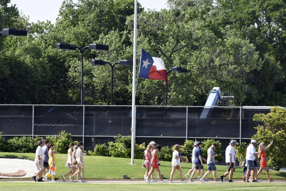 Fans walk past a Texas state flag that flies at half-staff out of respect for the community of Uvalde, Texas, which suffered a school shooting earlier in the week, during the third round of the Charles Schwab Challenge golf tournament at the Colonial Country Club, Saturday, May 28, 2022, in Fort Worth, Texas. (AP Photo/Emil Lippe)