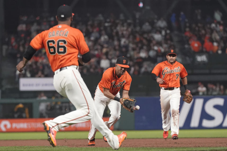 San Francisco Giants first baseman LaMonte Wade Jr., middle, commits a fielding error between pitcher Jarlin Garcia (66) and second baseman Donovan Solano on a ground ball hit by Pittsburgh Pirates' Ben Gamel during the seventh inning of a baseball game in San Francisco, Friday, July 23, 2021. (AP Photo/Jeff Chiu)