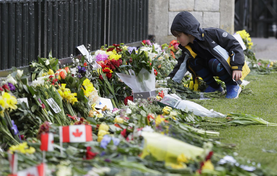 A child leaves flowers outside Windsor Castle in Windsor, England Sunday, April 11, 2021. Britain's Prince Philip, the irascible and tough-minded husband of Queen Elizabeth II who spent more than seven decades supporting his wife in a role that mostly defined his life, died on Friday. (AP Photo/Kirsty Wigglesworth)