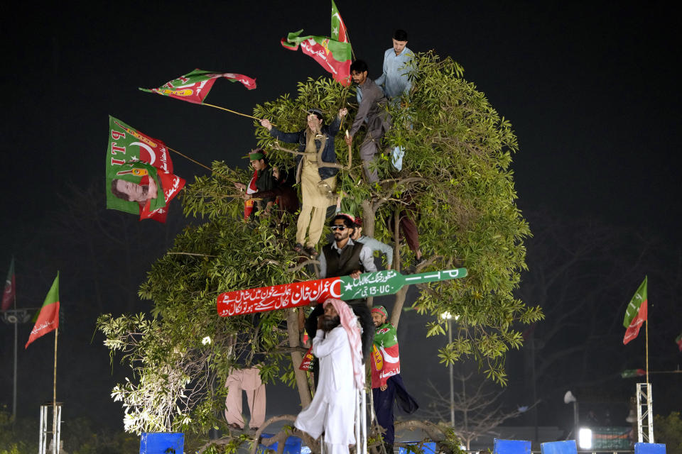Standing in a tree, supporters of former Prime Minister Imran Khan listen to his speech during a rally in Lahore, Pakistan, Sunday, March 26, 2023, to pressure the government of Shahbaz Sharif to agree to hold snap elections. (AP Photo/K.M. Chaudary)