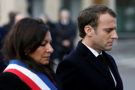 French President Emmanuel Macron (R) and Mayor of Paris Anne Hidalgo (L) attend a minute of silence as they stand in front of a commemorative plaque facing the 'Le Carillon' bar and 'Le Petit Cambodge' restaurant during a ceremony marking the second anniversary of the Paris attacks of November 2015 in which 130 people were killed, in Paris, France, November 13, 2017. REUTERS/Etienne Laurent/Pool