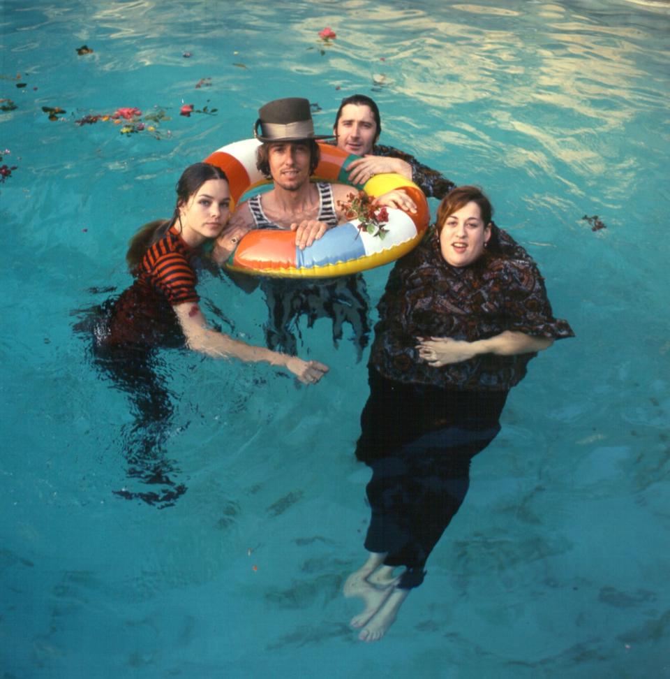 mama cass elliott, john phillips, michelle phillips, and denny doherty float in a pool in regular clothing while holding onto an inflatable ring