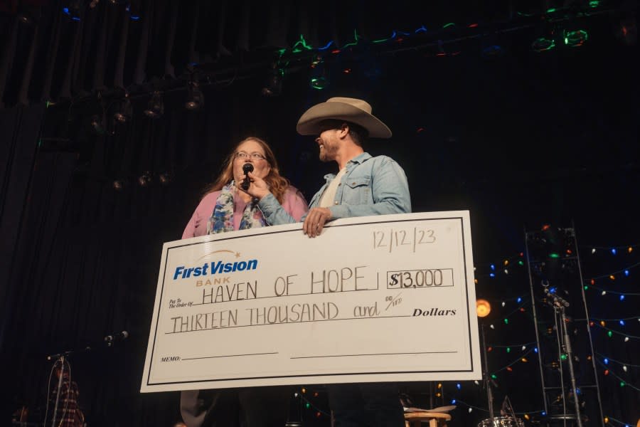 <em>Kellye Gilbert of Haven of Hope receives a $13,000 check from Dustin Lynch at the star’s annual benefit concert at his alma mater. (Photo: Jack Owens/Sweet Talk Publicity)</em>