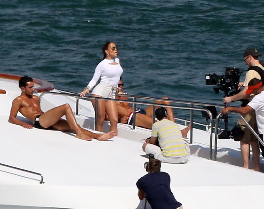 Never mind the half-naked men with the chiseled abs laying out in the sun beside her -- Jennifer Lopez stole the show as she turned her pout to the camera during a video shoot in Miami on Feb. 12, 2014.