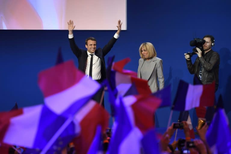 Emmanuel Macron and his wife Brigitte Trogneux salute the crowd after projections indicated the 39-year-old centrist led first round voting in France's presidential elections