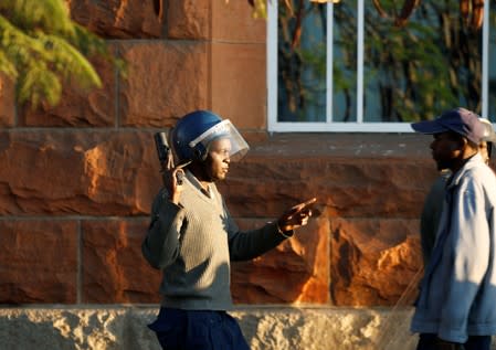 A riot police officer talks to a local as he keeps watch outside the Tredgold Building Magistrate court in Bulawayo