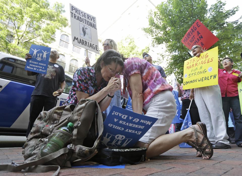 Members of the Family Foundation and supporters of traditional marriage, Barbara Kerns, of Midlothain, Va., left, and Linda Gagliardo, of Chester Va., pray outside the Federal Appeals Court in Richmond, Va., Tuesday, May 13, 2014. The 4th U.S. Circuit Court of Appeals in Richmond is taking up the issue of gay marriage, with arguments scheduled on a ruling that the state's ban on such unions is unconstitutional. (AP Photo/Steve Helber)