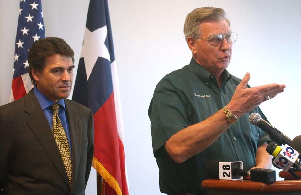 Texas Gov. Rick Perry (left) listens as  Corpus Christi Mayor Loyd Neal (right) answers questions from the media after Perry announced a $5 million loan to the City of Corpus Christi for military infrastructure improvements at the Congressman Solomon P. Ortiz Center on Oct. 13, 2004.