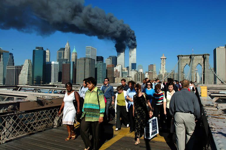 Los peatones cruzan el Puente de Brooklyn alejándose de las torres de World Trade en llamas antes de su derrumbe