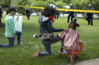 Ericka Ward-Audena, of Washington, puts her hand on her daughter Elle Ward-Audena, 7, as they take a knee in front of a police line during a protest of President Donald Trump's visit to the Saint John Paul II National Shrine, Tuesday, June 2, 2020, in Washington. "I wanted my daughter to see the protests, it's really important. I've gotten a million questions from her because of it," says Ward-Audena, "I think the most egregious statement was 'when they start looting, we start shooting.' That crossed a line for me." Protests continue over the death of George Floyd, who died after being restrained by Minneapolis police officers. (AP Photo/Jacquelyn Martin)