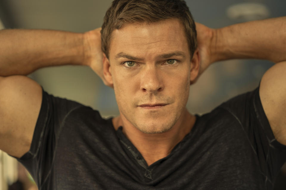 Alan Ritchson as Reacher with his hands behind his head